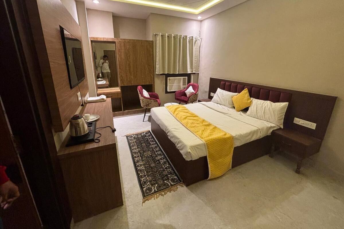 A modern hotel room with a large bed, a desk, a chair, a wardrobe, and a ceiling fan.