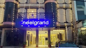 Entrada de um hotel com uma placa de neon que diz 'neelgrand'.
