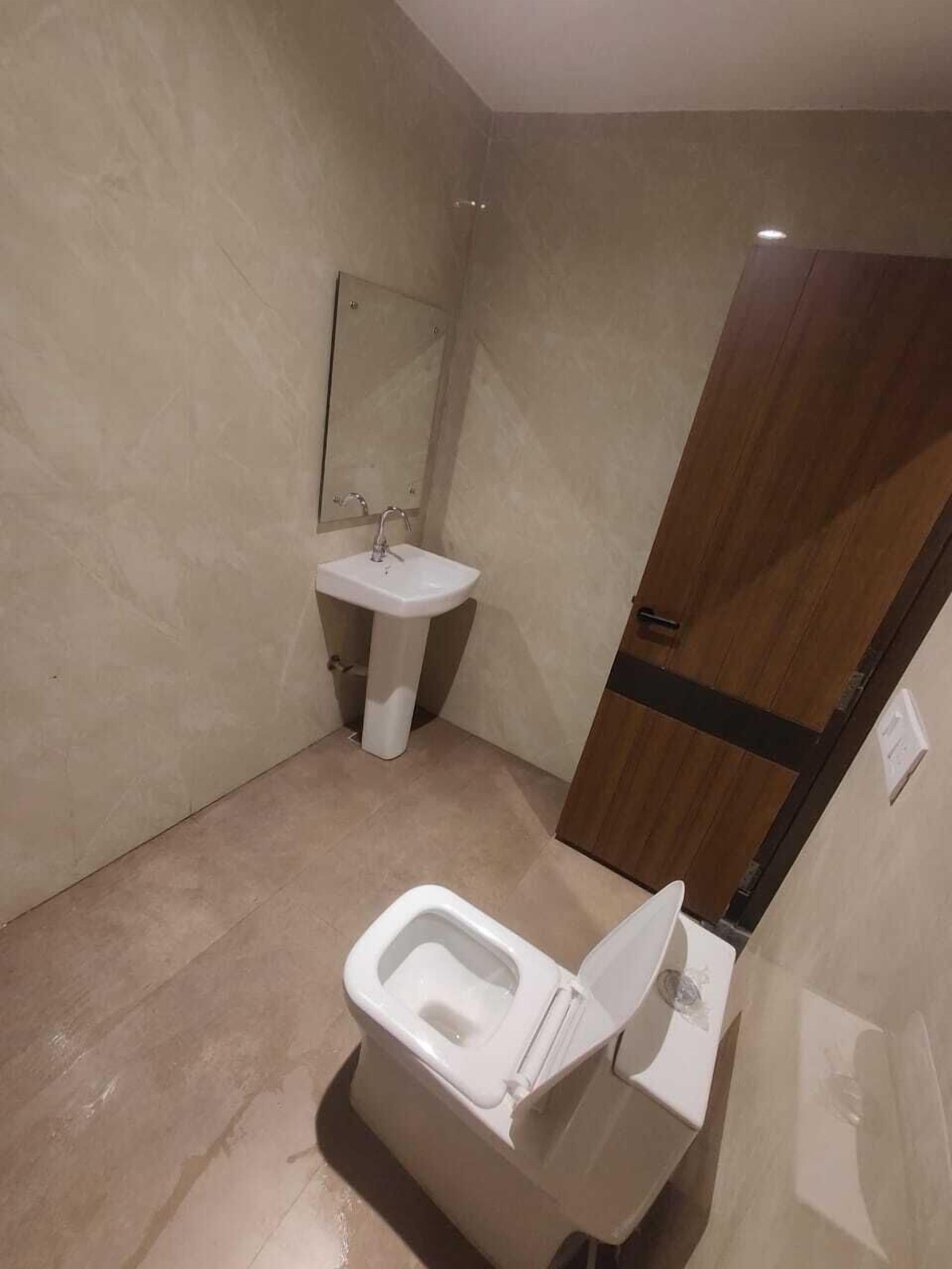A bathroom with a toilet, sink, and mirror.