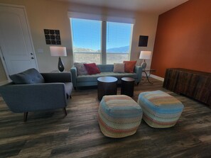 Ein Wohnzimmer mit einer Couch, zwei Hocker, einem Couchtisch und einem Beistelltisch.