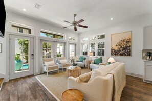A spacious living room with a ceiling fan, large windows, and a view of the outdoors. - Private Pool, Walk 2 Rosemary & Beach, Sleeps 10 (Inlet Beach)