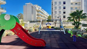 Ein Spielplatz mit Rutsche, Schaukeln und Wippe.