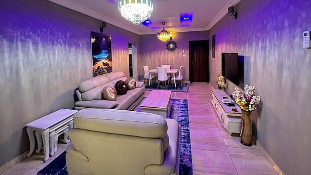 Ein modernes Wohnzimmer mit einer Couch, einem Esstisch und einer Pendelleuchte.
