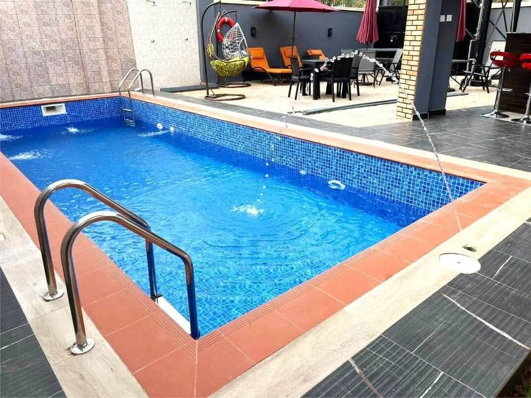 A rectangular swimming pool with a tiled edge, surrounded by a tiled deck.