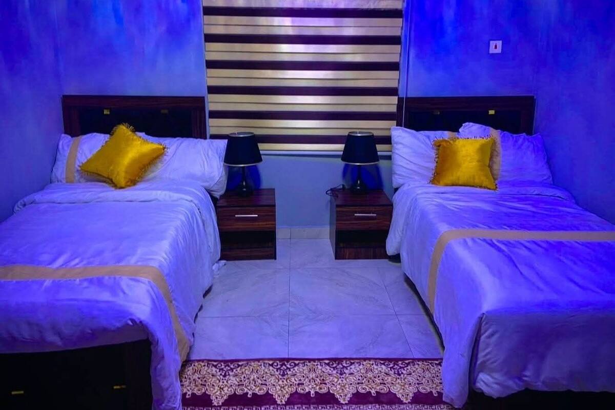 A twin bedroom with two beds, each with a nightstand and a lamp.