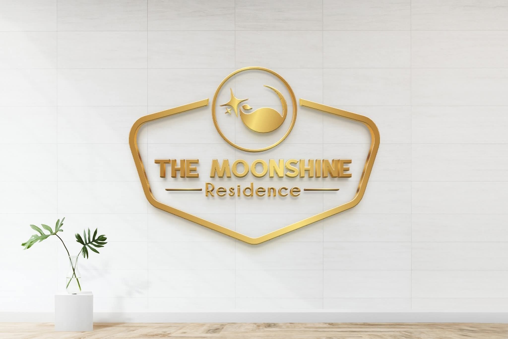 Logo for "The Moonshine Residence" med et stiliseret måne- og stjernedesign, monteret på en hvid flisetapet.