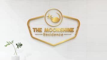 Logotipo de 'The Moonshine Residence' con un diseño estilizado de luna y estrella, sobre un revestimiento de baldosas blancas.