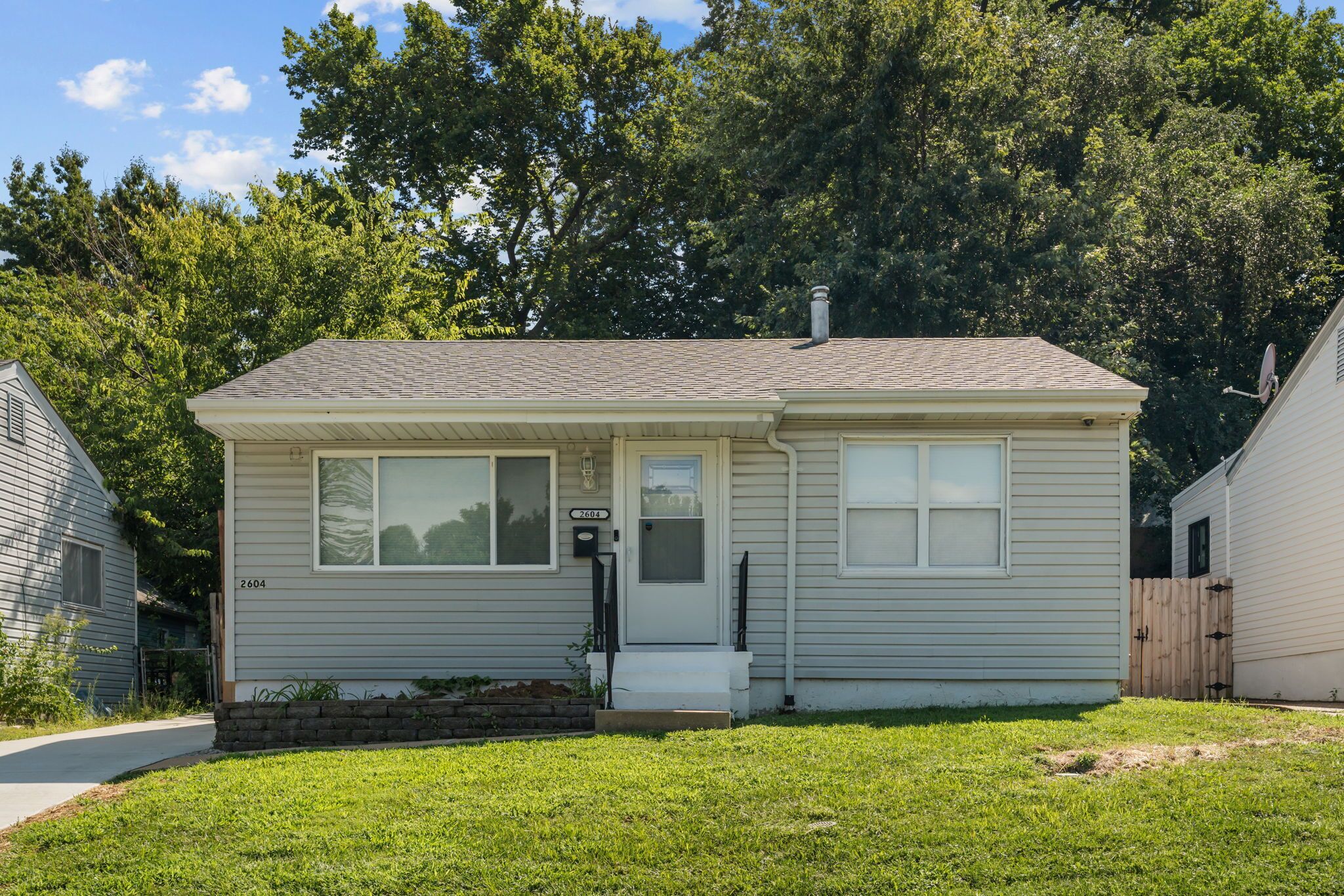 A single-story house with a front door, two windows, and a small front porch.