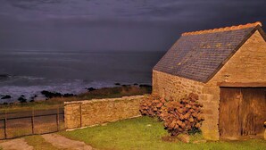 Ein Steinhaus mit Ziegeldach mit Blick auf das Meer.