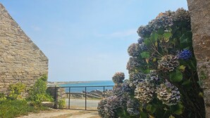 Eine Steinsäule, ein Metallgitter und Blick auf das Meer.