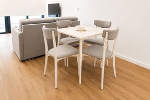 Un soggiorno moderno con un divano, un tavolo da pranzo con sedie e un televisore a parete.