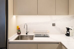 Una cucina moderna con lavello in acciaio inossidabile, scolapiatti e macchina per il caffè.