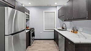 A modern kitchen with dark cabinets, stainless steel appliances, and a marble countertop. - Beautiful Bollywood 3 Bed Gem near Loyola University/Rogers Park/Lake Michigan (Chicago)