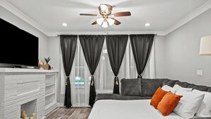 A modern bedroom with a fireplace, a large bed, a sofa, and a ceiling fan. - Beautiful Bollywood 3 Bed Gem near Loyola University/Rogers Park/Lake Michigan (Chicago)
