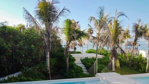 A swimming pool with a view of the sea, surrounded by palm trees and a wooden deck. - Akumal Hideout Sea Views 2 Min To Beach 11 Pools (Akumal)