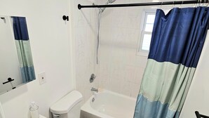 A bathroom with a toilet, sink, bathtub, and shower curtain. - Apartment located in vibrant Montclair 2-blocks to NYC trains (Montclair)