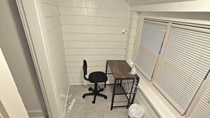 A small, narrow room with white walls and a tiled floor. There is a desk with a chair, a window with blinds, and a trash can. - Apartment located in vibrant Montclair 2-blocks to NYC trains (Montclair)
