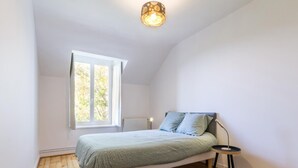 Quarto com cama, janela, radiador e abajur.
