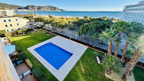 A swimming pool surrounded by a well-maintained lawn, with a view of the sea and a distant mountain. - MIL.LENI I. Dúplex con encanto y vistas al mar en Roses – ¡Disfruta del paseo marítimo! (Roses)