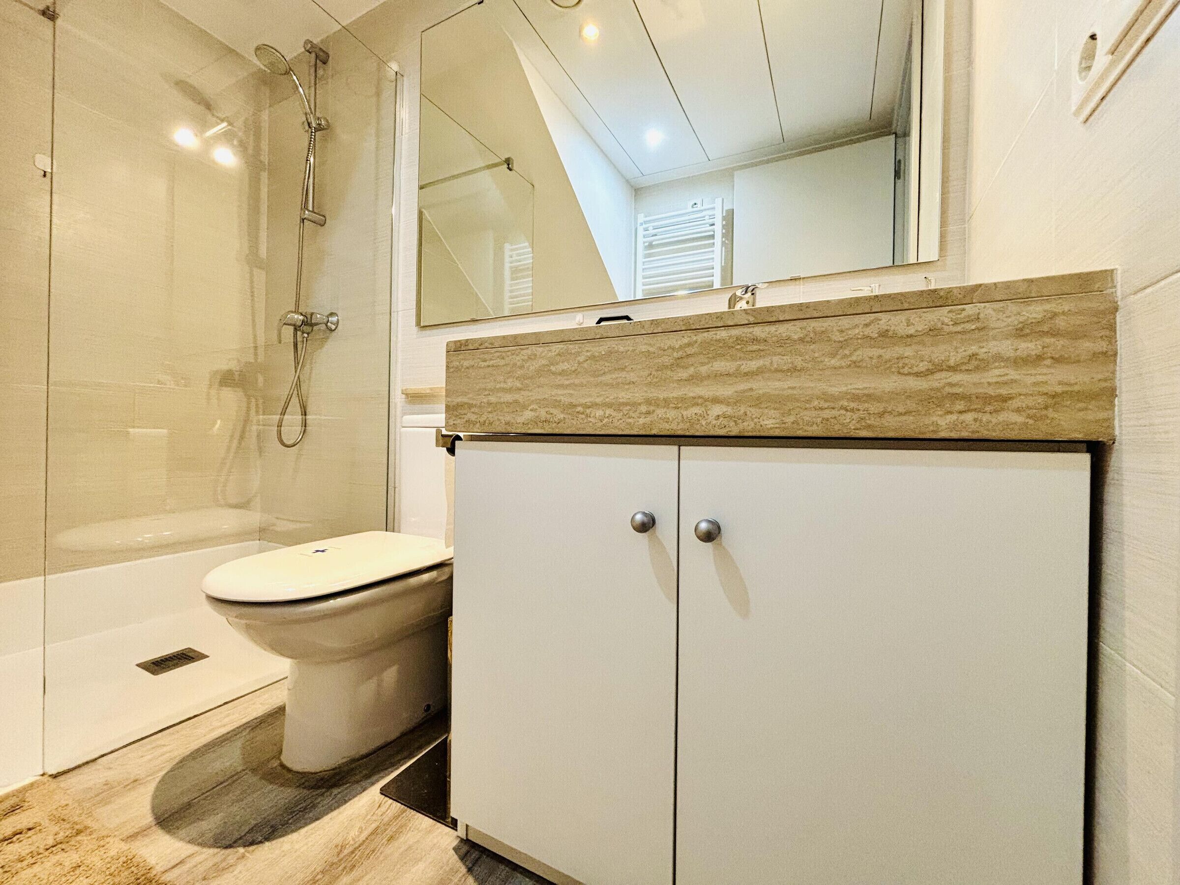 Une salle de bain avec une douche, des toilettes et un meuble de rangement.