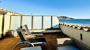 A terrace with chairs and a wicker sofa overlooking a beach. - MIL.LENI I. Dúplex con encanto y vistas al mar en Roses – ¡Disfruta del paseo marítimo! (Roses)
