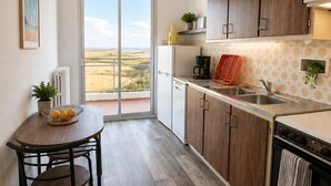 Una cocina compacta con vistas al campo, un comedor con mesa y sillas, y armarios de madera.