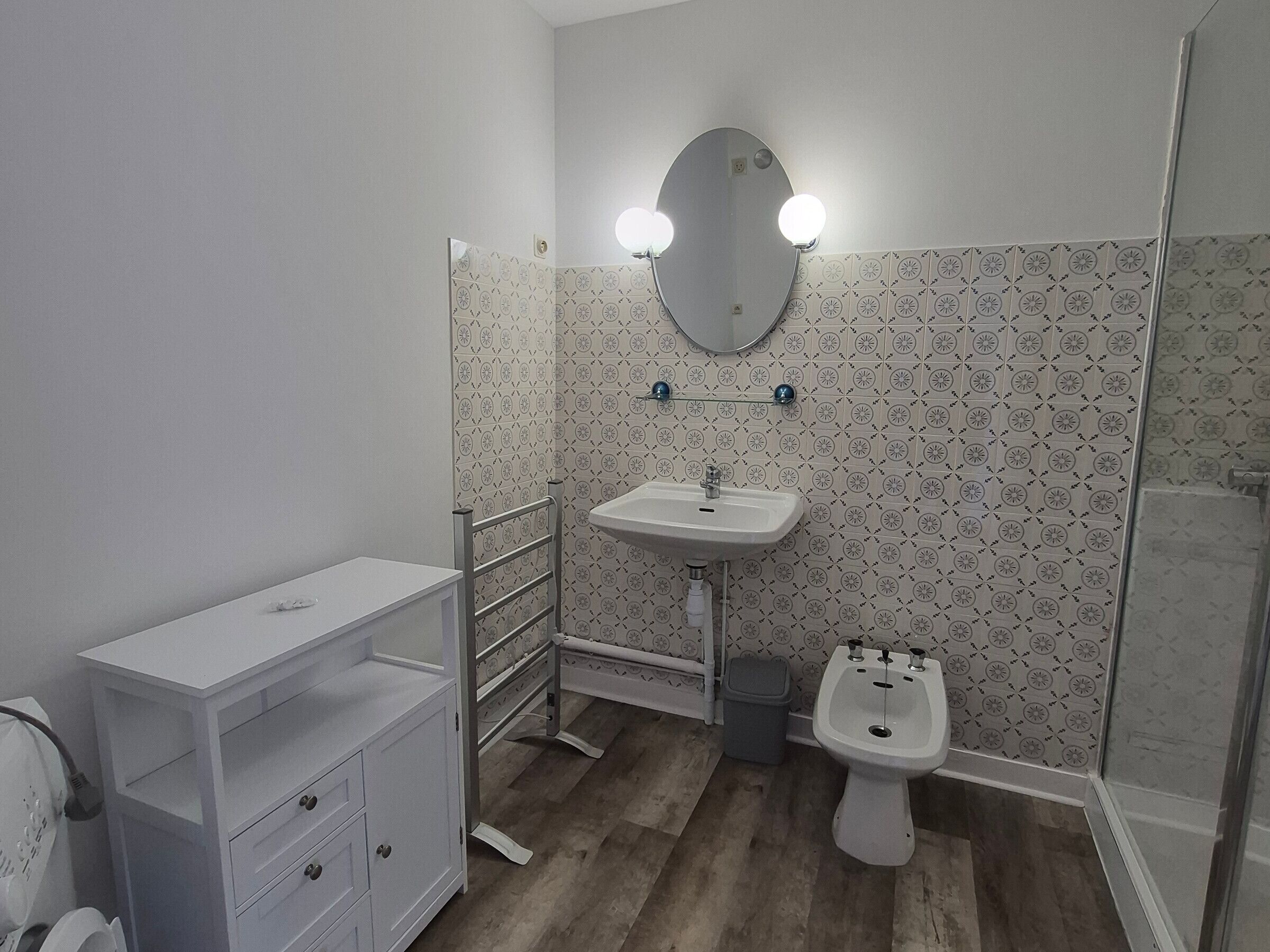 A bathroom with a sink, mirror, vanity, and bidet.