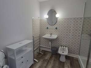 Une salle de bain équipée d’un lavabo, d’un miroir, d’un meuble-lavabo et d’un bidet.
