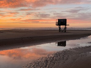 Une tour de surveillance des sauveteurs sur une plage au coucher du soleil.