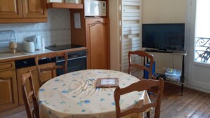 A kitchen with wooden cabinets, a microwave, a toaster, and a dining table with chairs. - Family apartment for 4 in the heart of La Bourboule (La Bourboule)