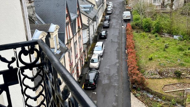 A narrow street lined with parked cars and residential buildings. - Family apartment for 4 in the heart of La Bourboule (La Bourboule)
