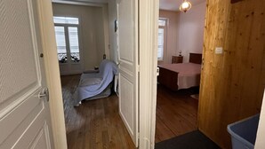 A bedroom with a wooden floor, a bed, a bedside table, and a window with blinds. - Family apartment for 4 in the heart of La Bourboule (La Bourboule)