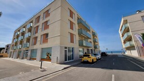 Un immeuble à plusieurs étages doté de balcons, d’un espace de stationnement et offrant une vue sur la mer.
