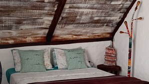 Ein Schlafzimmer mit schrägen Wänden, einem Bett mit floralem Bettbezug und einem kleinen Nachttisch.
