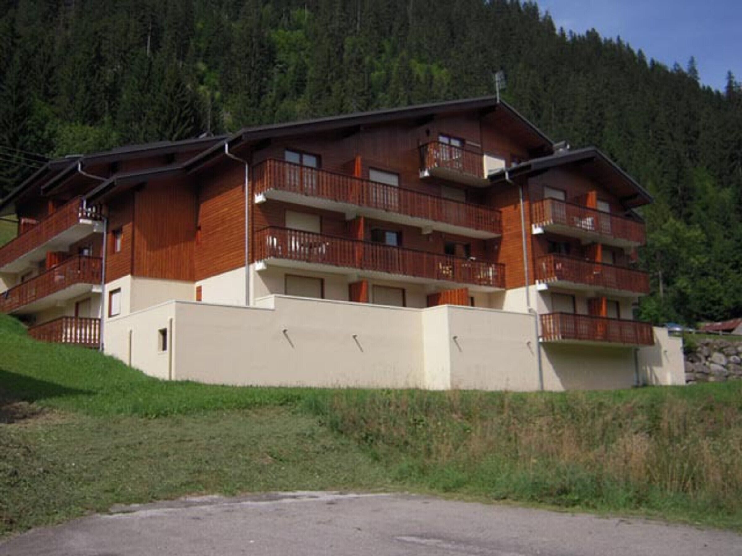 Un immeuble en bois à plusieurs étages, doté de balcons, qui se dresse sur une colline boisée.