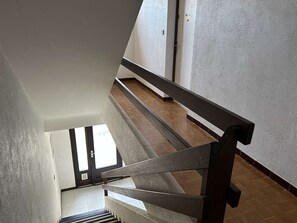 A staircase with a wooden handrail and a view of a tiled floor leading to a door. - 3-room Apartment Near the Beach, Sleeps 6 in Saint-Pierre-la-Mer (Fleury-Saint-Pierre-la-Mer)