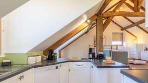 A kitchen with white cabinets, a black countertop, and wooden beams on the ceiling. - Cozy countryside cottage, 2 bedrooms, open views (Baugé en Anjou)