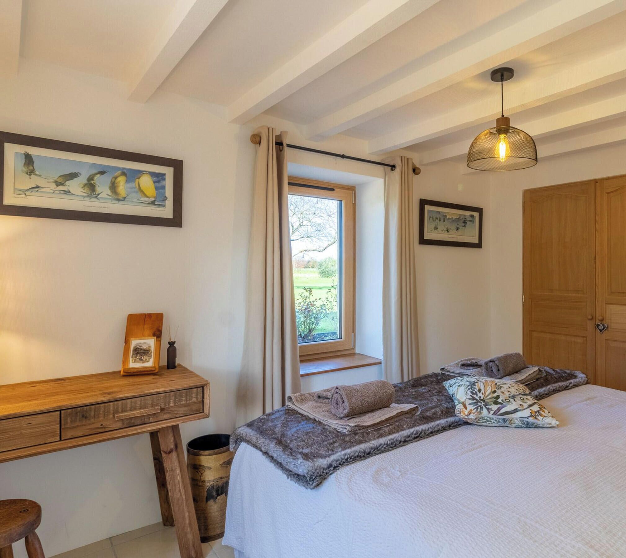 Ein Schlafzimmer mit Bett, Schreibtisch, Fenster und Tür.