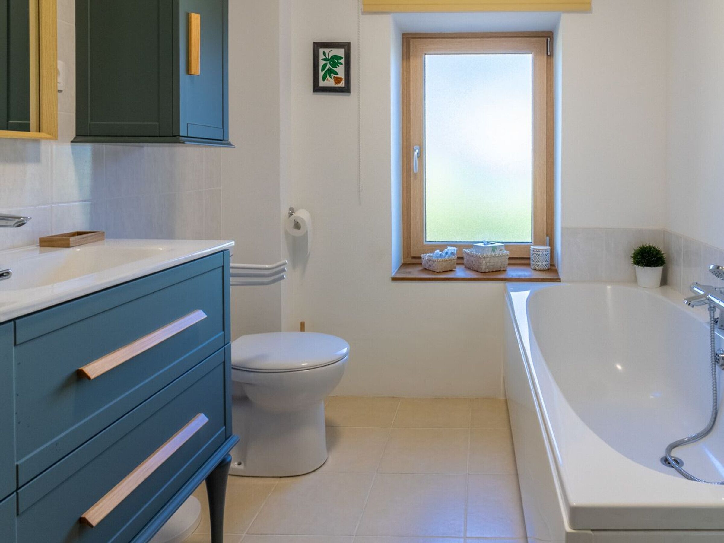 Een badkamer met toilet, wastafel, bad en een raam met uitzicht.