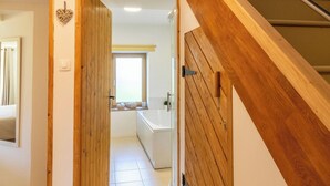 A hallway leading to a bathroom with a window, wooden walls, and a tiled floor. - Cozy countryside cottage, 2 bedrooms, open views (Baugé en Anjou)