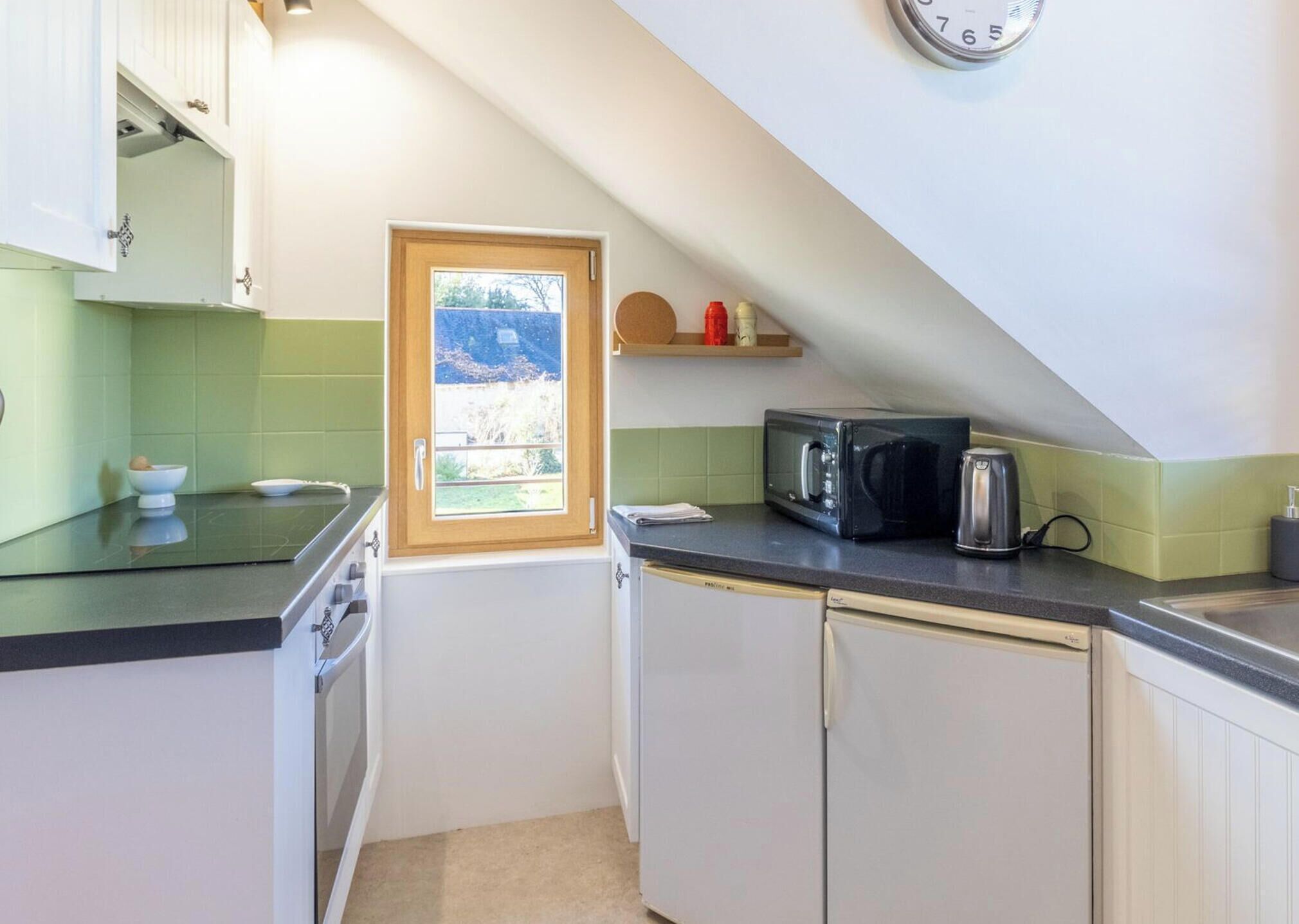 Eine kleine Küche mit Fenster, Mikrowelle und Toaster.