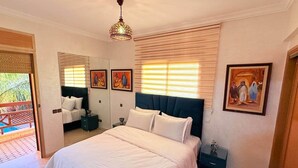 Ein Schlafzimmer mit einem großen Bett, Nachttischen, einem Spiegel und Bildern an den Wänden.