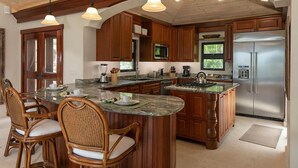 A kitchen with wooden cabinets, a central island, a refrigerator, and pendant lighting. - Enjoy the life at Villa Adagio, St John, Chocolate Hole in t (Cruz Bay)
