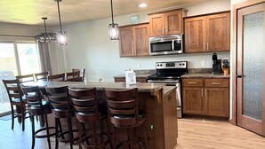 Una cocina con armarios de madera, un microondas de acero inoxidable, una estufa y una zona de bar con taburetes.
