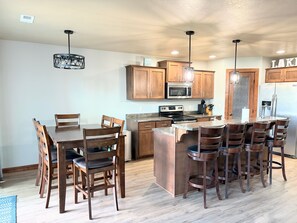 A kitchen with wooden cabinets, a central island, and bar stools. - Family-friendly cabin with ideal proximity to pool (Arnolds Park)