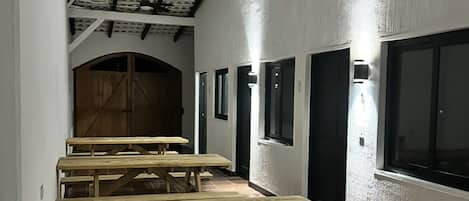Un couloir avec des bancs en bois, un ventilateur de plafond et un sol carrelé.