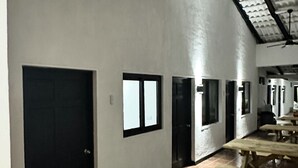 A spacious indoor area with tiled flooring, a high ceiling with exposed beams, and multiple windows along the walls. - Hotel Cool Breeze (El Cuco)