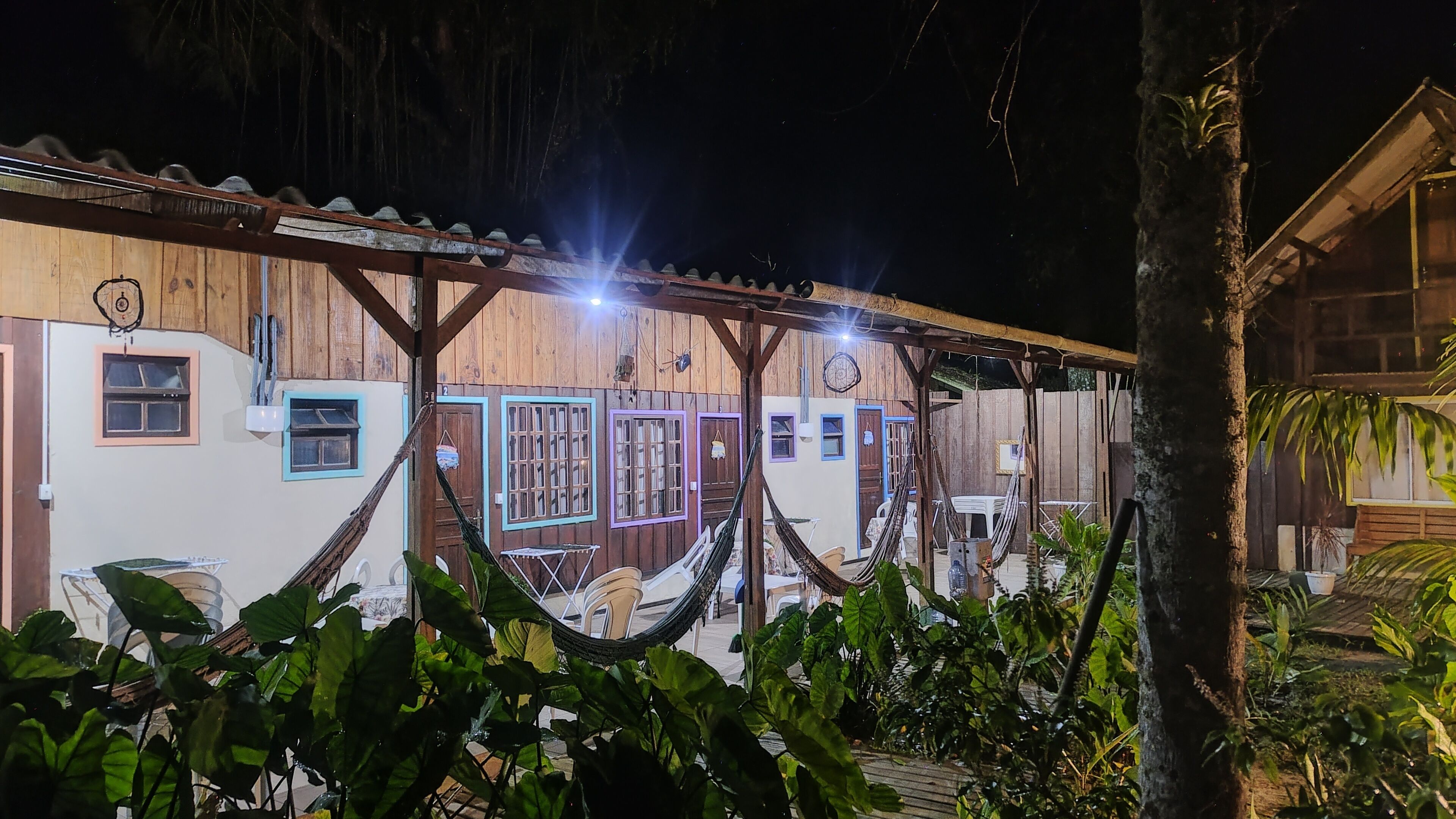 Il s’agit d’un bâtiment en bois comprenant plusieurs pièces, chacune étant dotée d’une fenêtre et d’une porte. À l’extérieur, on trouve des hamacs et des chaises.