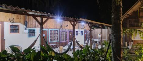 Il s’agit d’un bâtiment en bois comprenant plusieurs pièces, chacune étant dotée d’une fenêtre et d’une porte. À l’extérieur, on trouve des hamacs et des chaises.