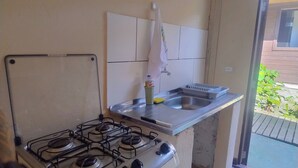 Een compacte keuken met een gasfornuis, een spoelbak en een klein aanrecht.